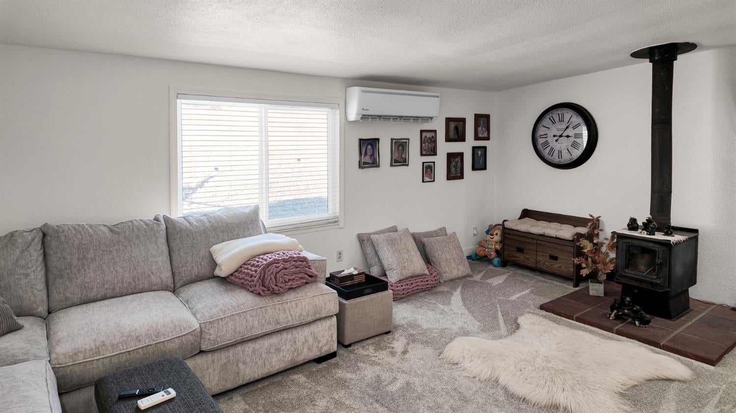 Furnished living room with a gray sectional sofa and black wood stove.