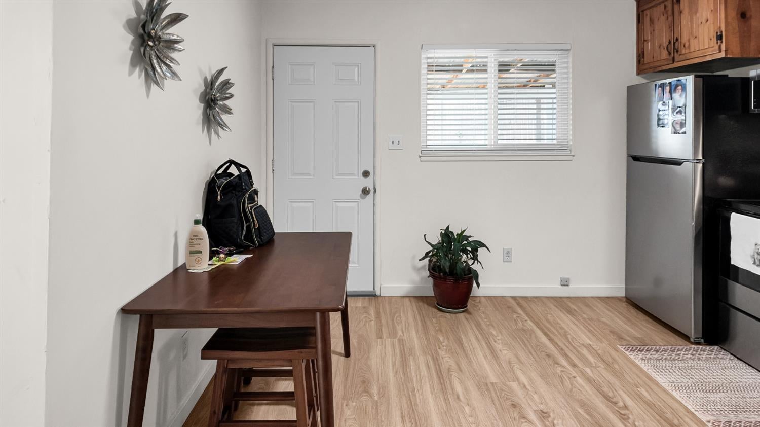 Kitchen and dining area with a dark wood table, stainless steel appliances, and light wood flooring.