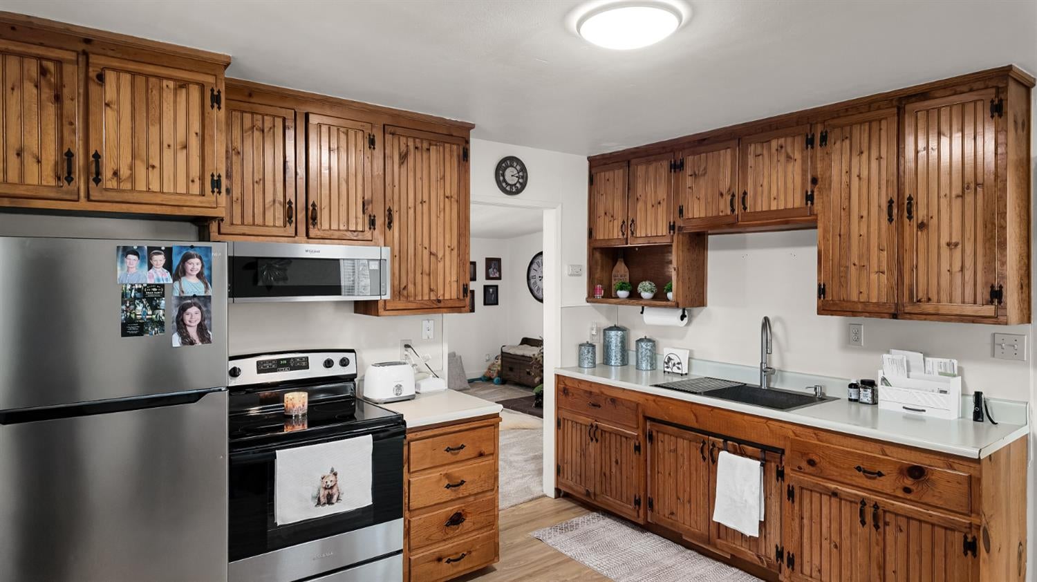 Kitchen with knotty wood cabinets, white counters, stainless refrigerator, and electric range.