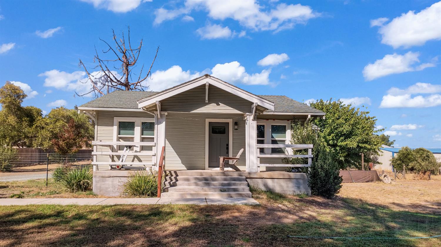 Single-story gray house with a covered porch, white trim, and front steps.