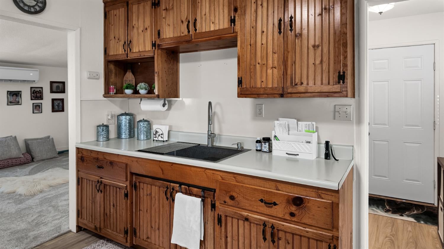 Kitchen with extensive warm wood cabinetry, a long white countertop, and a black sink.