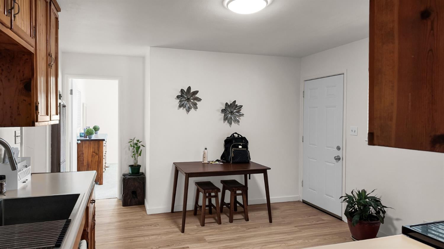 Kitchen and dining area with wood cabinetry, a small table and stools, and wood-look flooring.