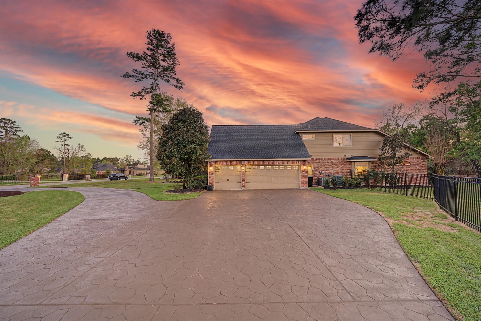 Two-story brick-and-siding home with a wide garage and stamped-concrete driveway at sunset.