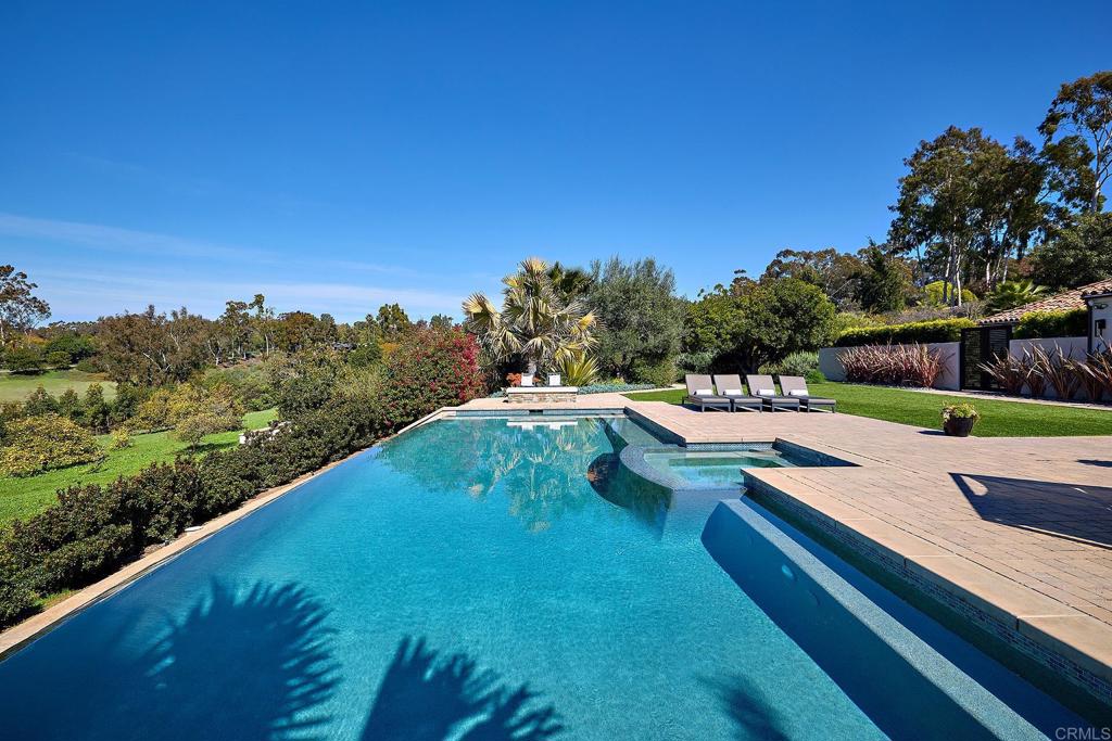 Clear blue swimming pool surrounded by palm trees and greenery