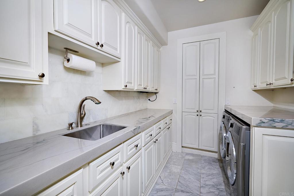 Laundry room with white cabinetry and granite countertop