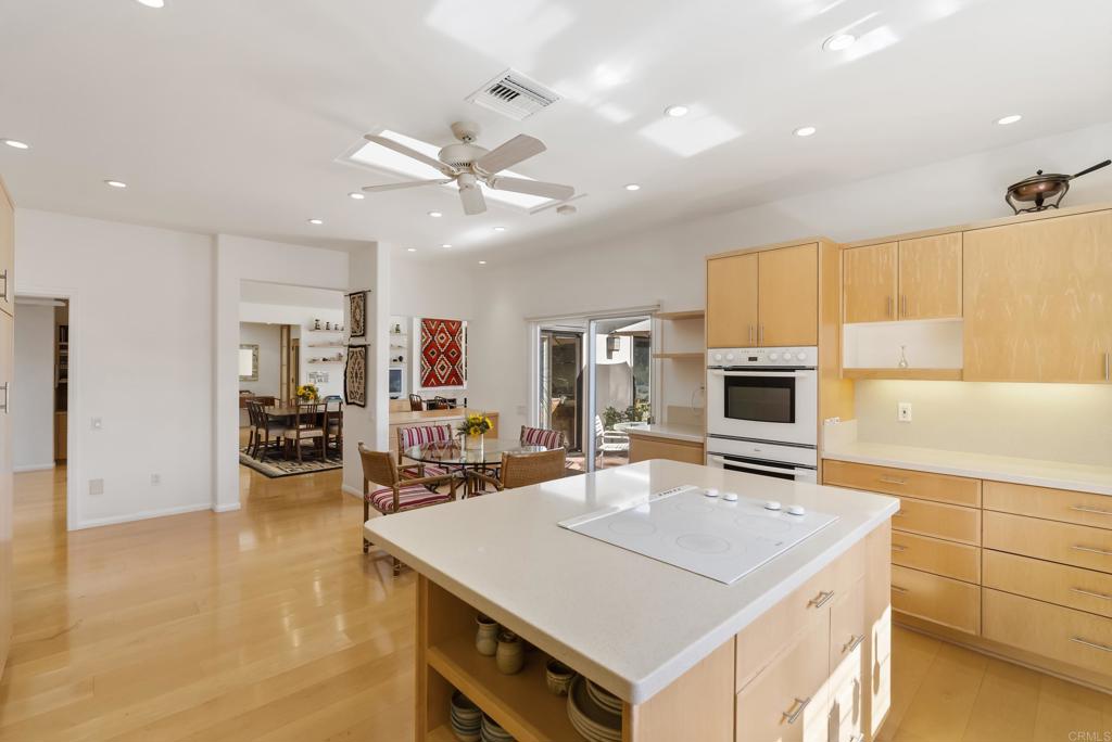 Bright open kitchen with center island, light wood cabinets, and stainless steel appliances