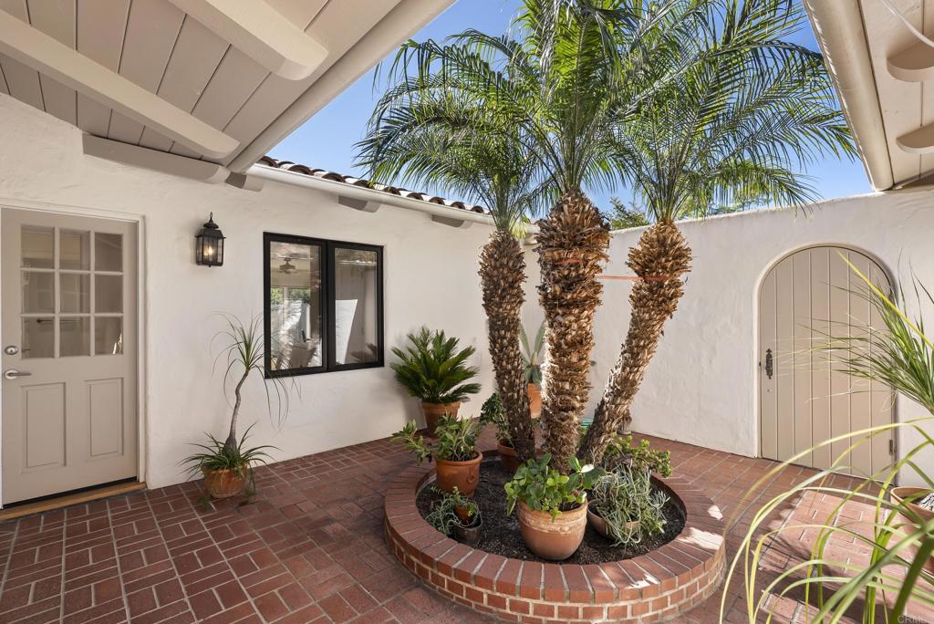 Charming courtyard entry with mature landscaping and brick patio