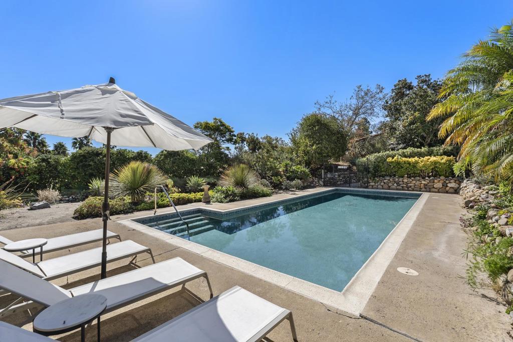 Poolside lounge area with greenery and hillside backdrop
