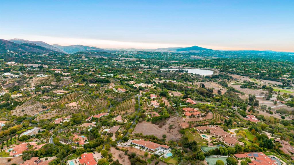 Wide aerial view of Rancho Santa Fe with surrounding homes, greenery, and mountains