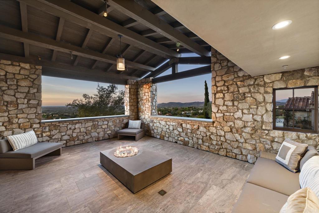 Covered stone patio with seating overlooking Santaluz golf course