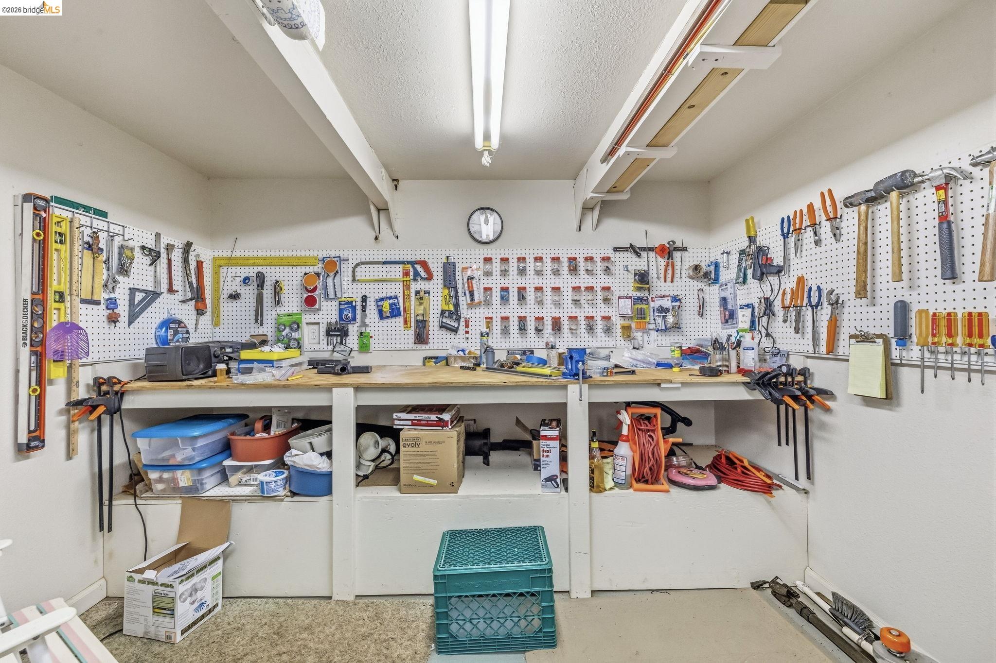 Workshop with a long workbench and hand tools organized across wall-mounted pegboards.