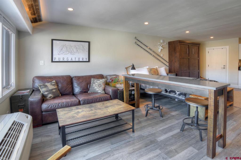 Condo living area with a leather sofa, breakfast bar, and framed Purgatory sign.