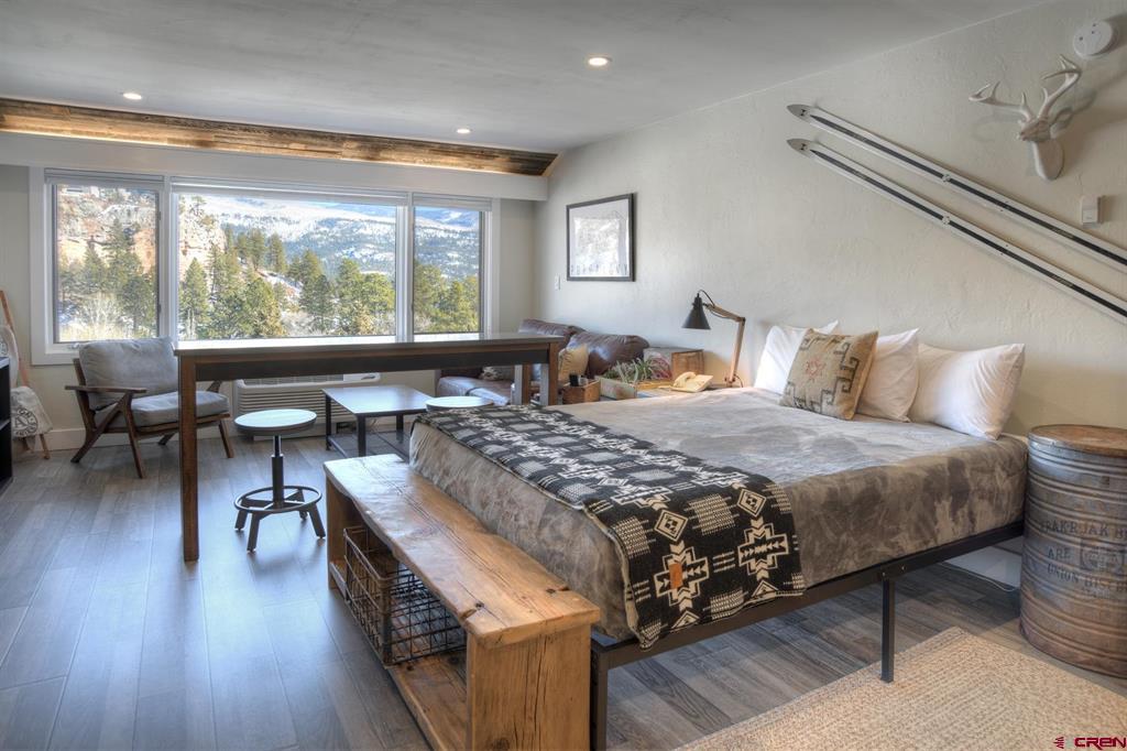 Furnished bedroom with skis mounted on the wall and mountain views through large windows.