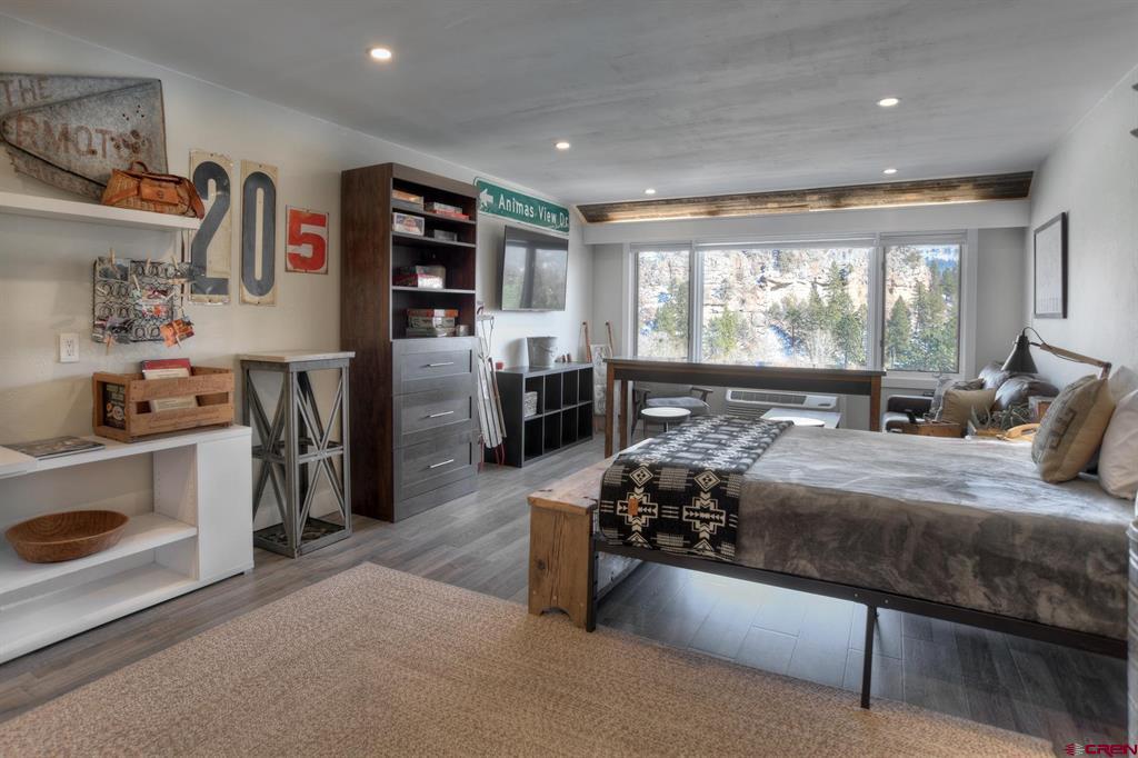 Furnished bedroom with a large bed and wide windows overlooking snow-dusted mountain scenery.