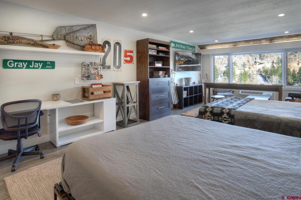 Bedroom with two beds, ski-themed decor, and large windows overlooking a rocky mountain slope.