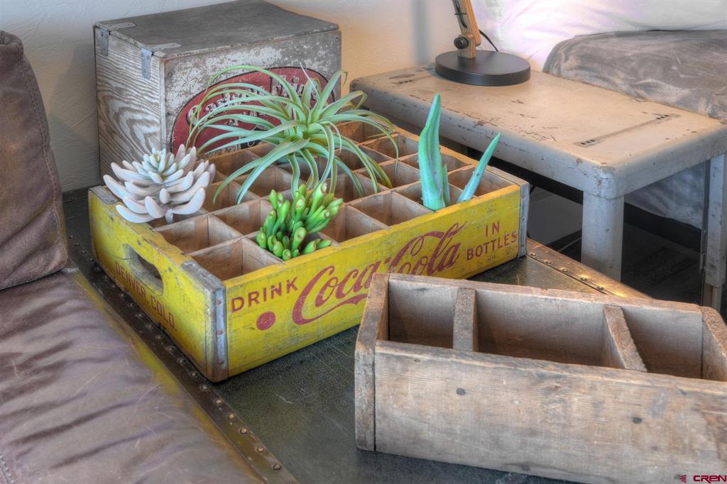 Succulents in a vintage yellow Coca-Cola crate beside rustic wooden crates and a sofa.