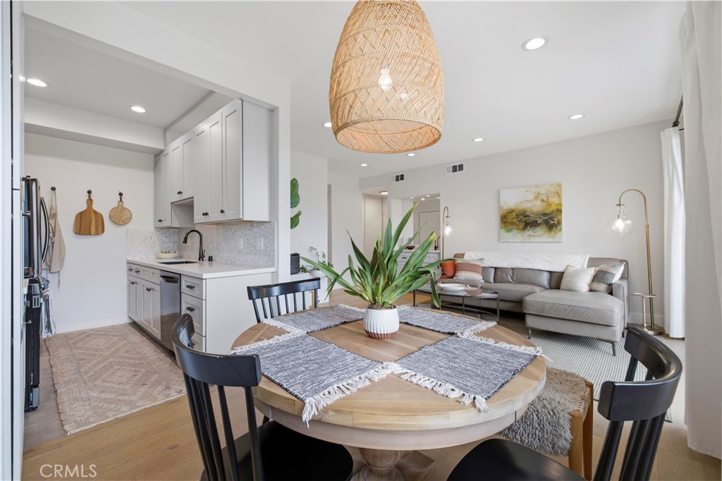 Open-plan kitchen and living room with a round dining table and gray sectional sofa.