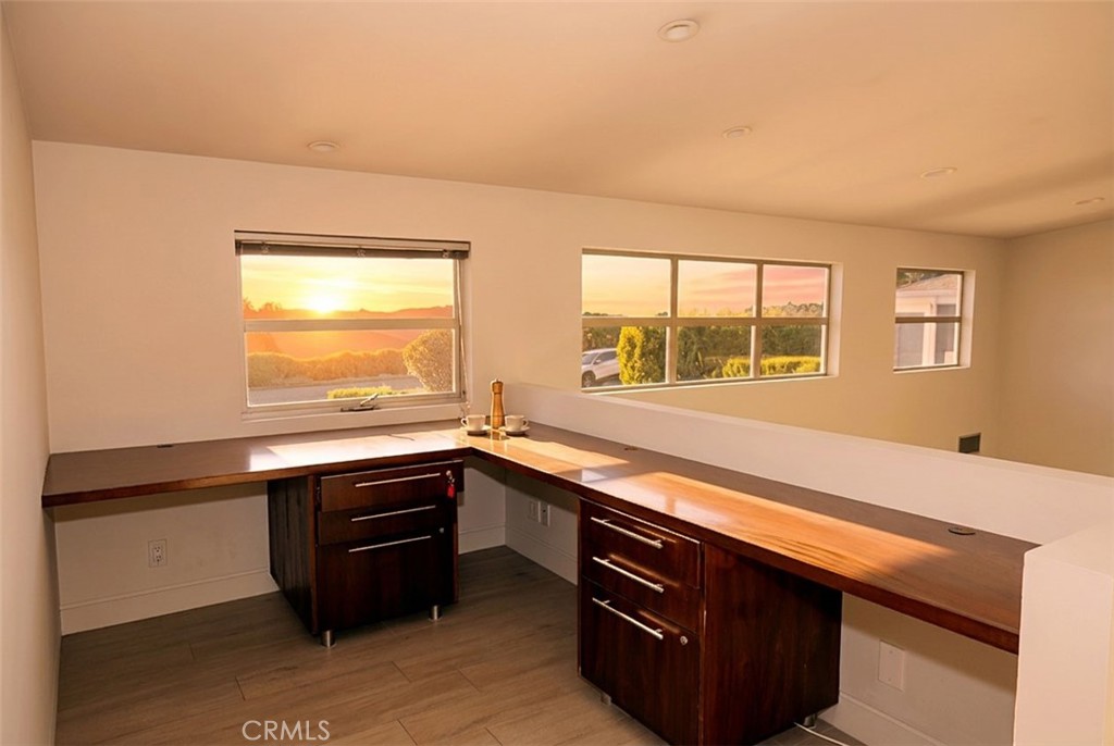 Interior workspace with L-shaped wood counters and windows overlooking greenery and hills.
