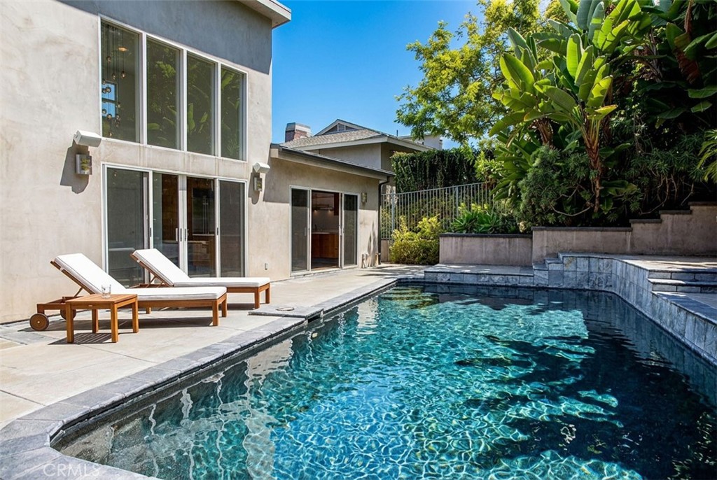 Laguna Beach home with a swimming pool, two lounge chairs, and tropical greenery.