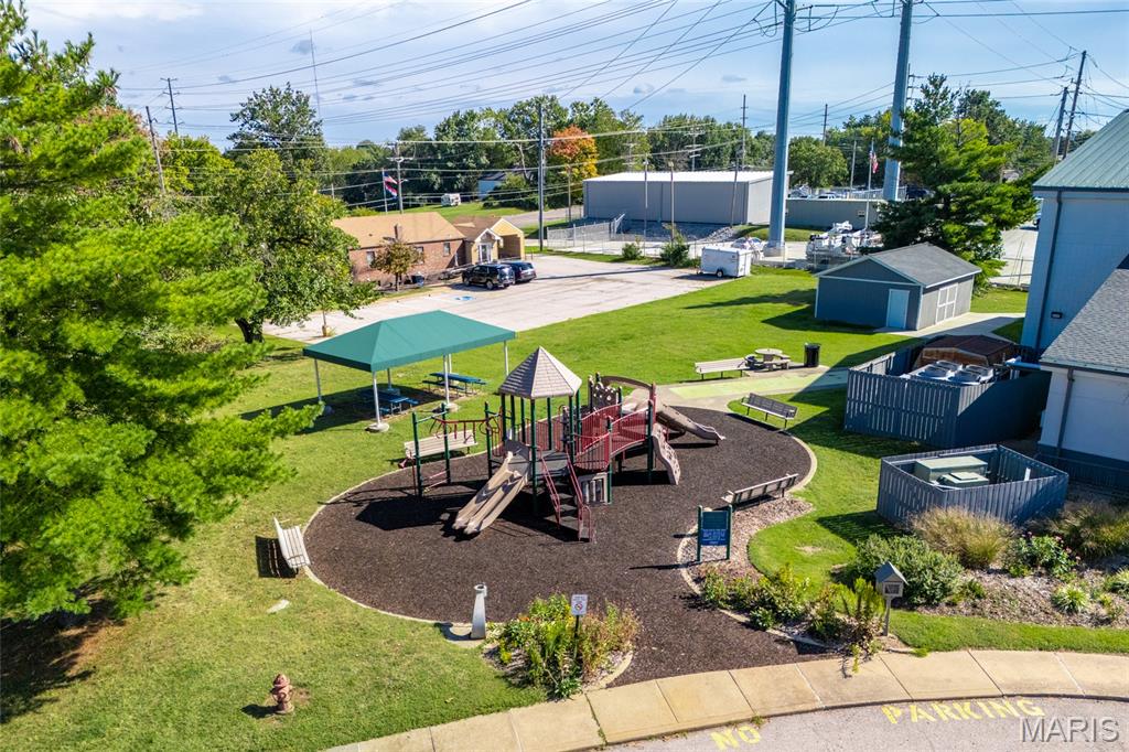 Aerial view of a community playground with play equipment, a pavilion, and surrounding buildings.
