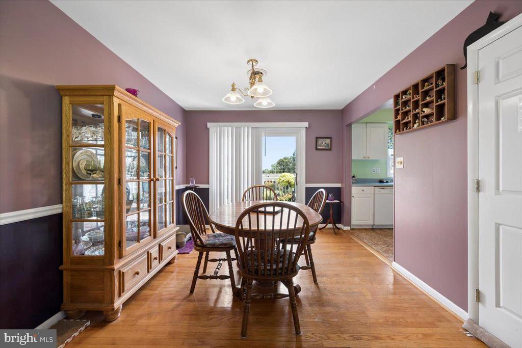 Dining room with mauve walls, a round wooden table, hardwood floors, and a glass-front china cabinet.