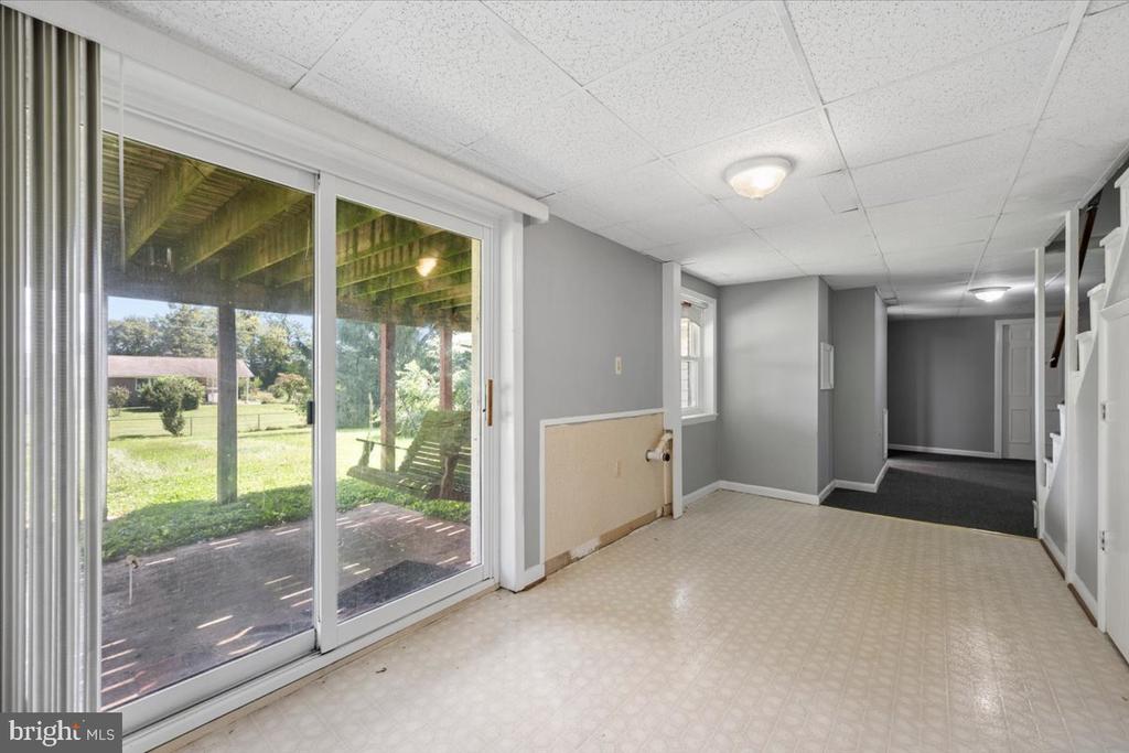Basement room with sliding glass doors opening to a covered patio and grassy backyard.