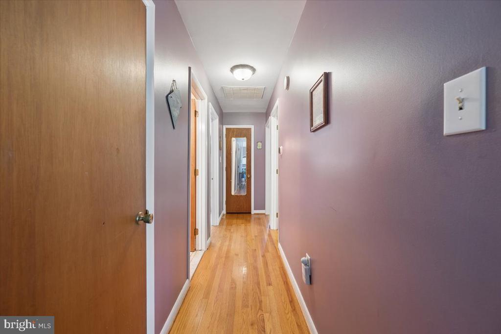 Hallway with hardwood floors, mauve walls, and multiple doorways.