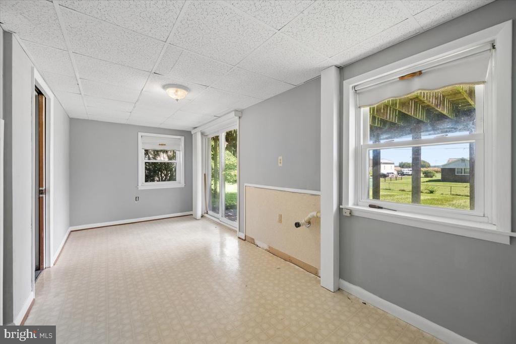 Vacant kitchen with plumbing hookups, two windows, and a sliding glass door to the yard.