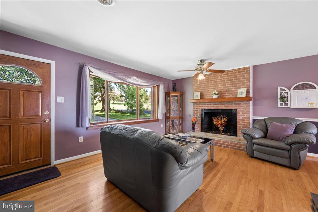 Living room with a brick fireplace, purple walls, hardwood floors, and leather sofas.