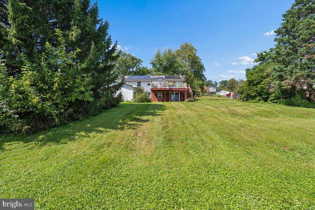 Rear exterior of a home with a raised deck and broad grassy yard.