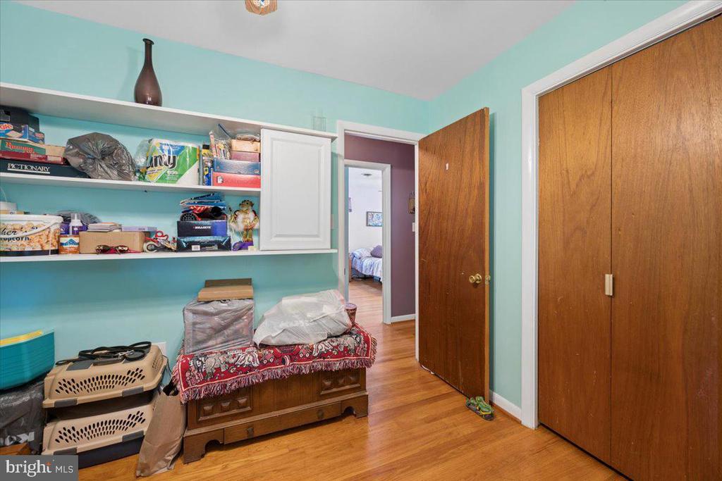Turquoise room with open shelves, wooden closet doors, hardwood floors, and a carved chest.