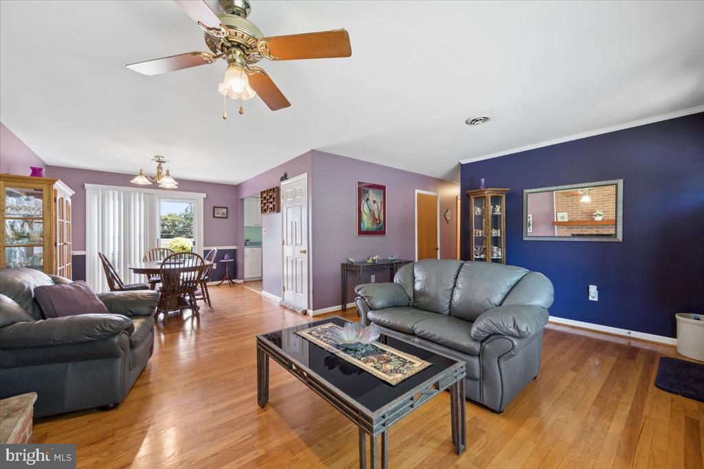 Living room with gray leather sofas and hardwood floors, opening into a dining area.