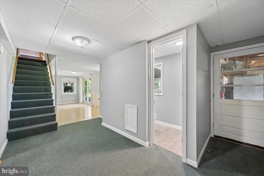 Hallway with green carpet, a staircase, and doorways to adjoining rooms.