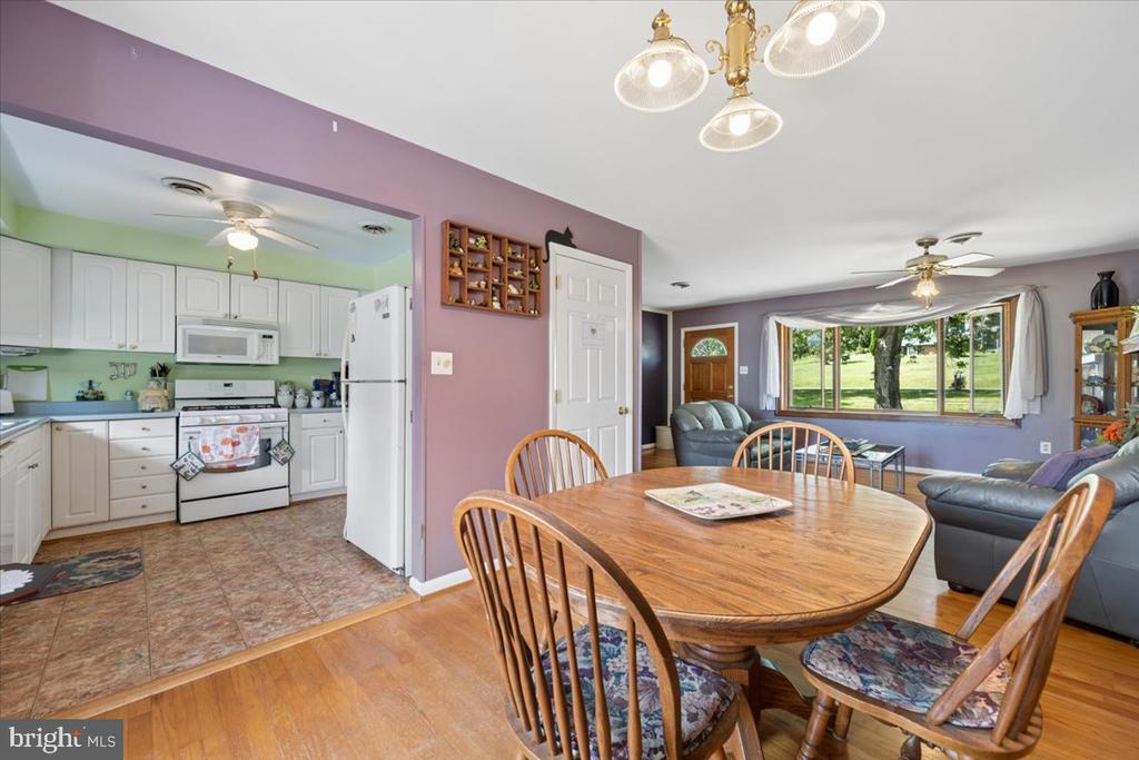 Open kitchen and dining area with white cabinets, a round wooden table, and windows overlooking the yard.