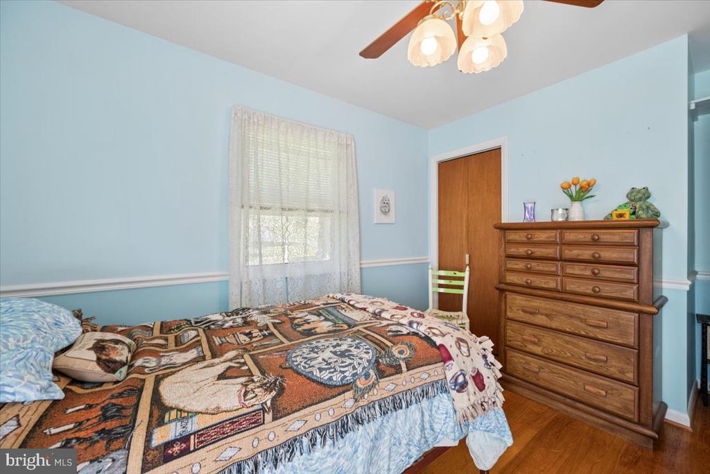 Bedroom with blue walls, a patterned bedspread, and a tall wooden dresser.