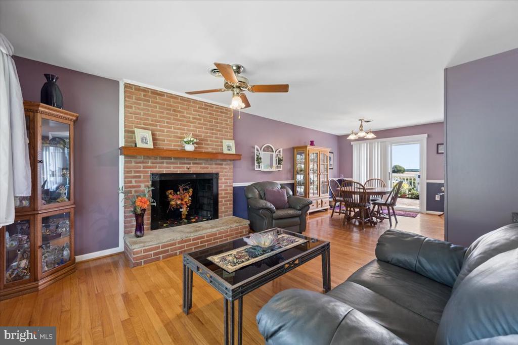 Living room with brick fireplace, hardwood floors, and adjoining dining area.