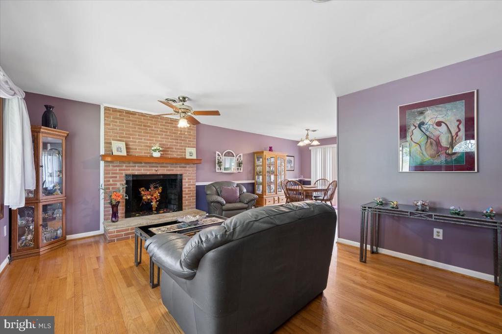 Living room with a brick fireplace, purple walls, hardwood floors, and leather seating.