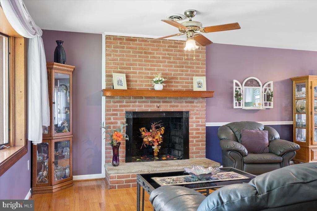Living room with a brick fireplace, purple walls, hardwood floors, and leather seating.