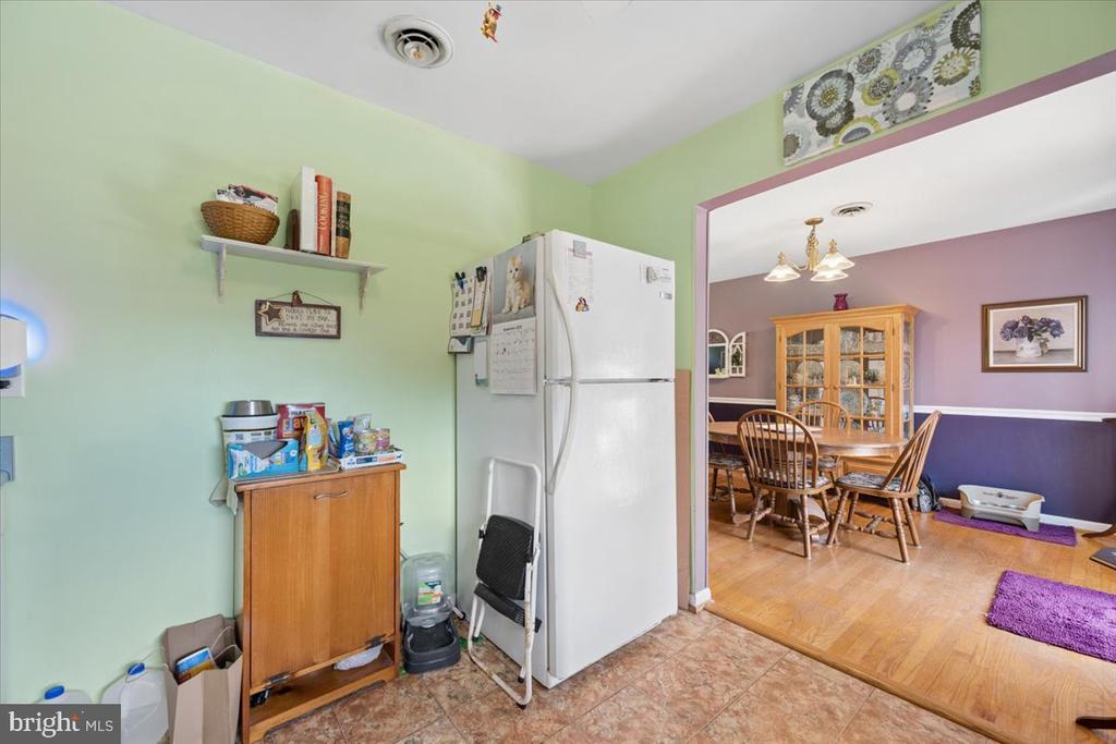 Kitchen with pale green walls and white refrigerator, opening into a purple dining room with a wooden table.