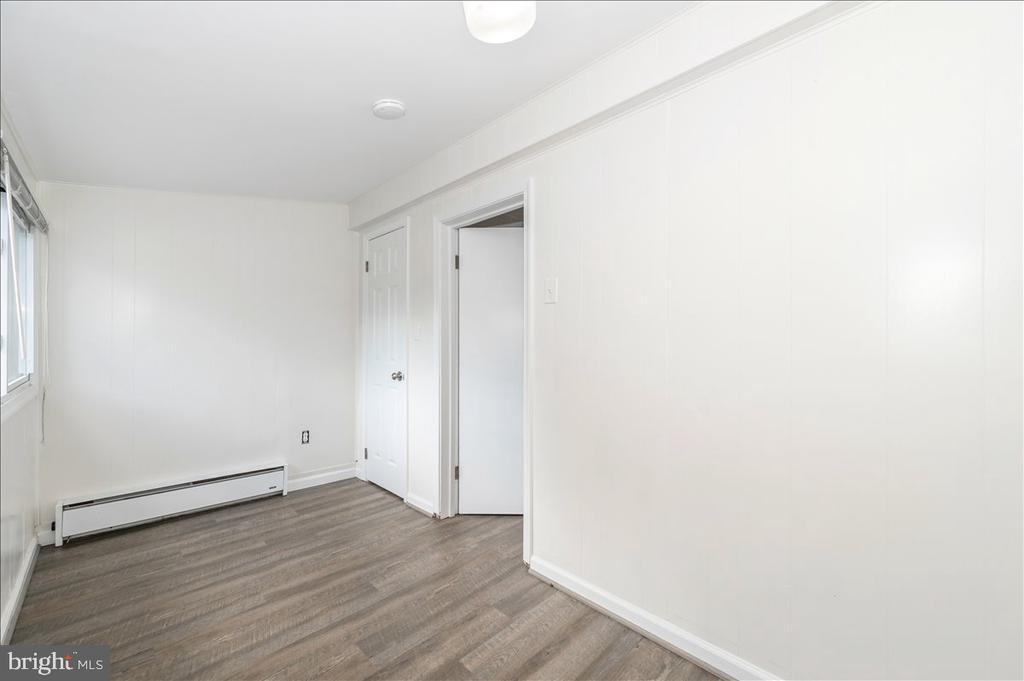 Empty room with gray wood-look flooring, a window, and a baseboard heater.