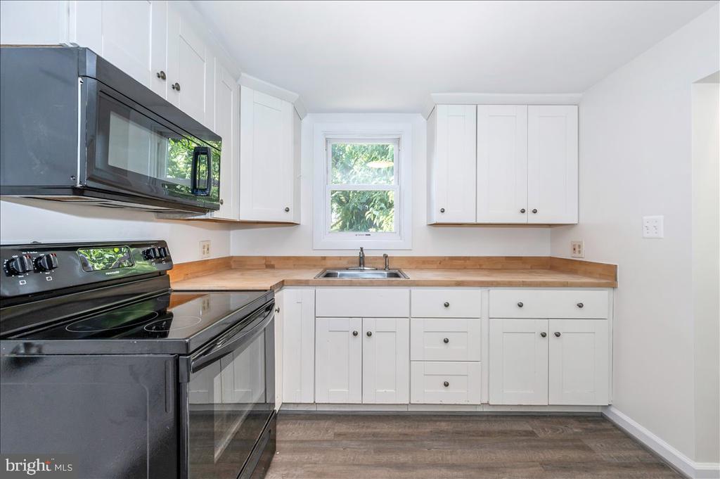 Kitchen with white cabinets, wood countertops, and a window above the sink.