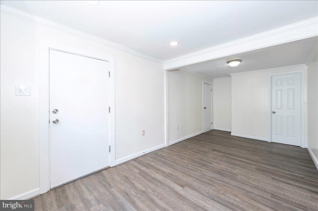 Empty room with crown molding, gray-brown plank flooring, and white doors.