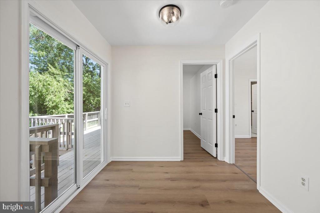 Vacant room with wood-look floors and sliding glass doors opening onto a deck.