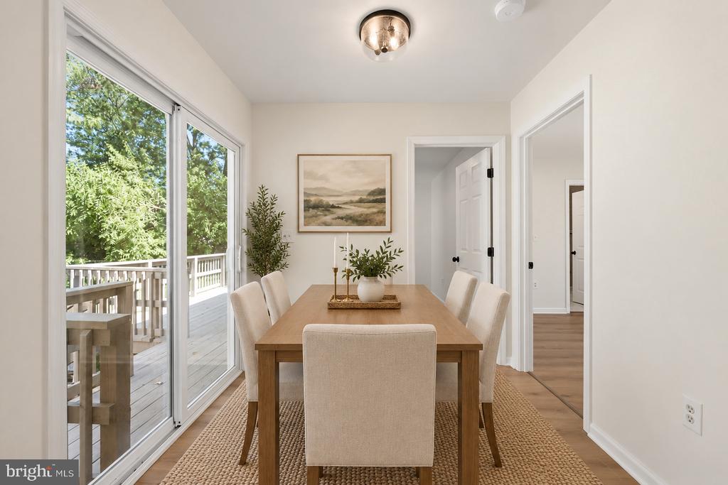 Dining room with a wooden table beside sliding glass doors opening onto a deck.