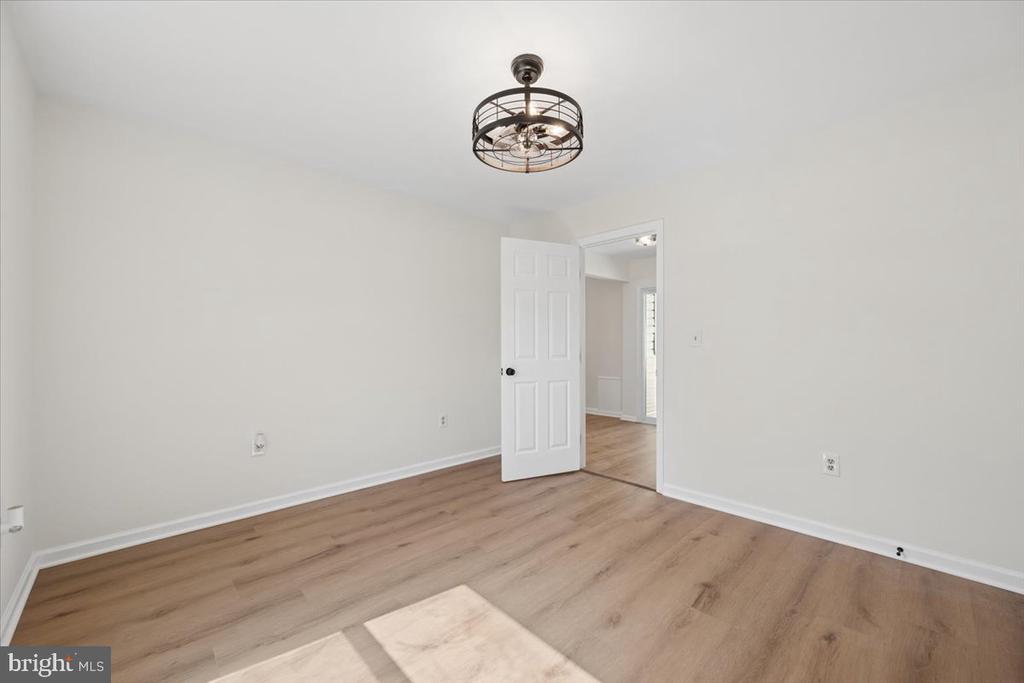 Empty room with wood-look flooring, a metal ceiling light, and an open doorway.
