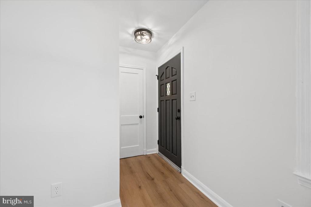 Entry hallway with wood flooring and a dark paneled front door.