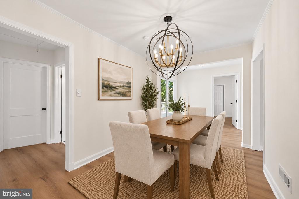 Dining room with a wood table, beige chairs, woven rug, and sculptural chandelier.
