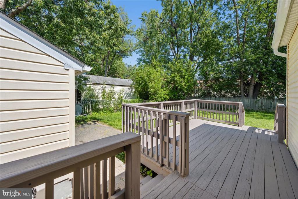 Rear deck with gray railings overlooking a grassy, tree-lined yard.