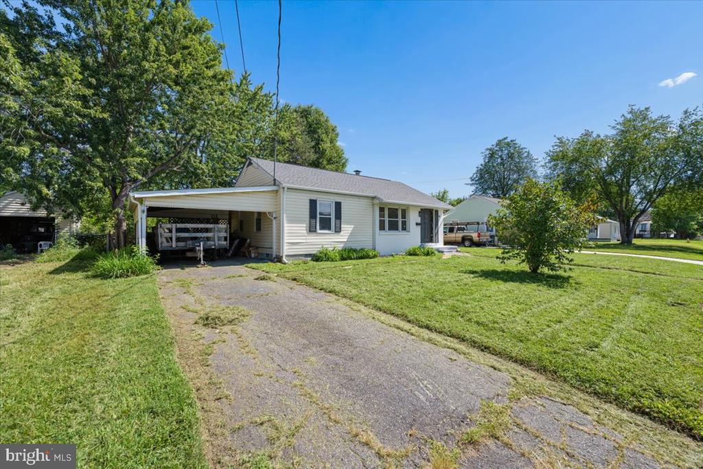 Single-story house with a carport, paved driveway, and broad front lawn.