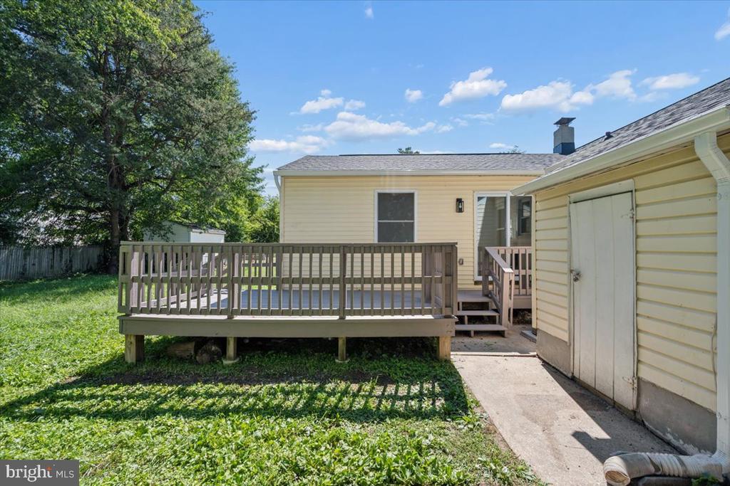 Rear exterior with a raised wooden deck, grassy yard, and detached shed.